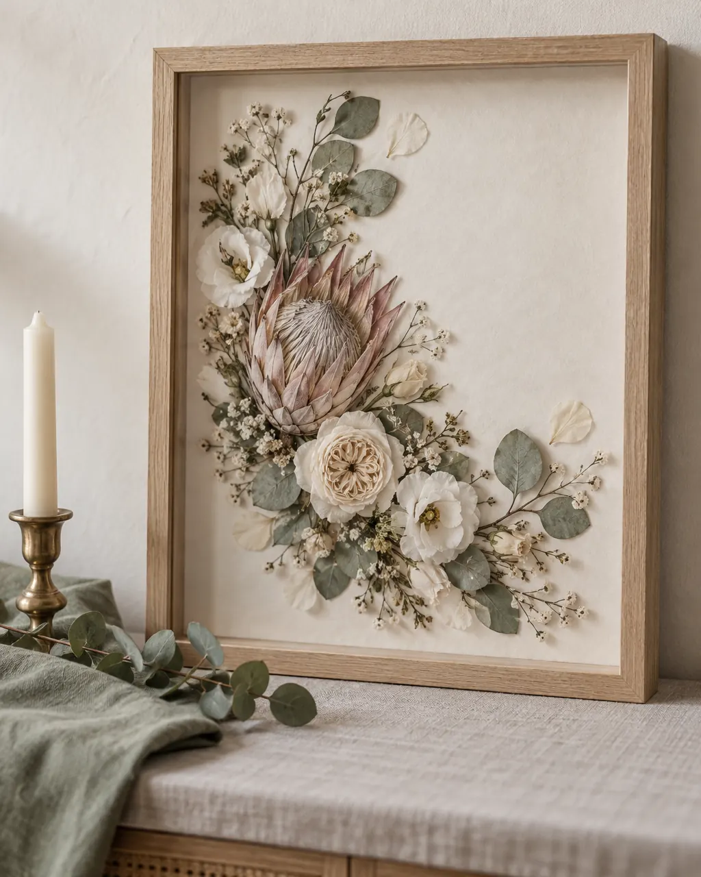 A preserved bridal bouquet with a king protea, ivory roses and eucalyptus, pressed and framed in pale oak.