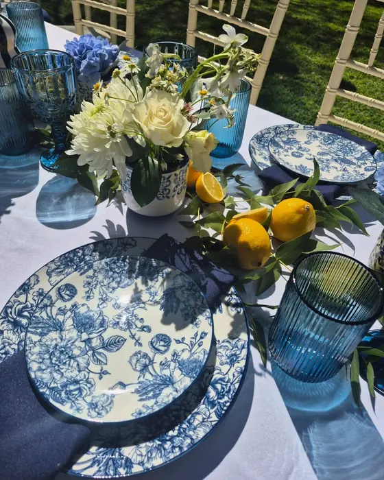 Blue-and-white floral china, a blue glass and a posy of white flowers and lemons.