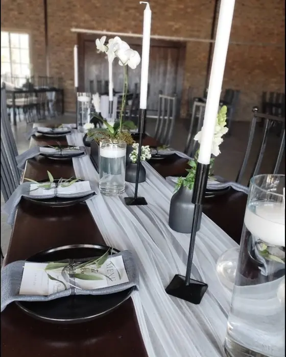 White orchids, tall white taper candles in black holders and floating candles down a white runner.